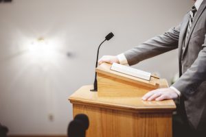 male-formal-outfit-preaching-holy-bible-from-tribune-altar-church