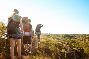 Young beautiful friends travelers with backpacks walking in canyon. Copy space.